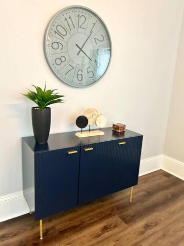 a blue cabinet with a clock on the wall at Downtown Charm, 3 Bdr, Near Rest and Bars in Winston-Salem