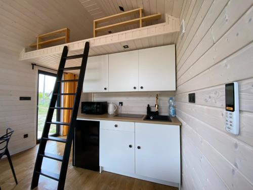 a kitchen with white cabinets and a ladder in a tiny house at Przytulne Kątno in Kątno