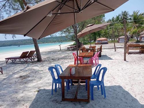 een groep tafels en stoelen onder een parasol op het strand bij JIJI KOH RONG in Kaôh Rŭng (3)