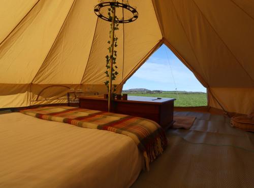 a tent with a bed and a table in it at Rescorla Retreats- Poldark in Mevagissey