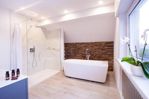 オーステンデにあるVilla in front of the sea with natural swimming pondの白い浴槽とシャワー付きのバスルーム