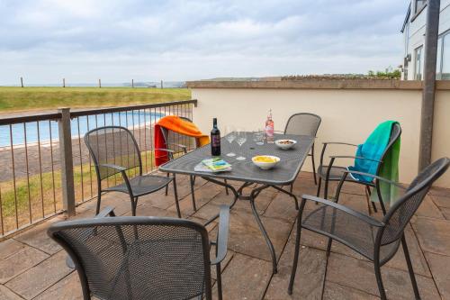 a patio with a table and chairs on a balcony at 2 Ocean's Edge in Hope-Cove