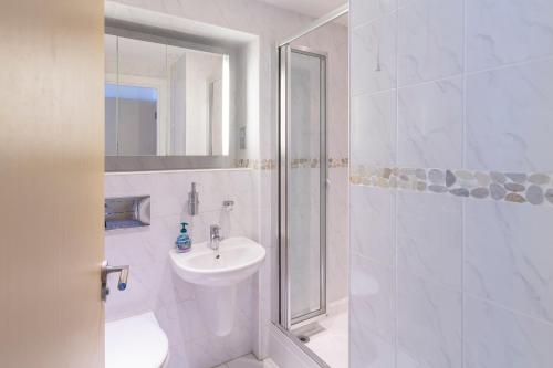 a white bathroom with a sink and a shower at 2 Ocean's Edge in Hope-Cove