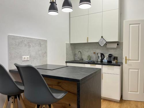 uma cozinha com um balcão preto e duas cadeiras em Urban Citytrip Flat - 15 min to Center em Viena