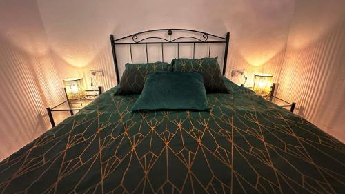 Troglorent - Maison Troglodyte في Terque: سرير مع لحاف أخضر ومصباحين