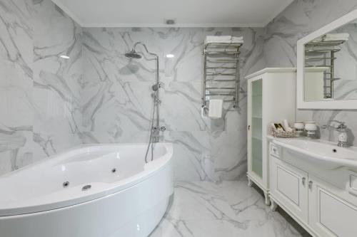 a white bathroom with a tub and a sink at Sagora Hotel in Chernivtsi