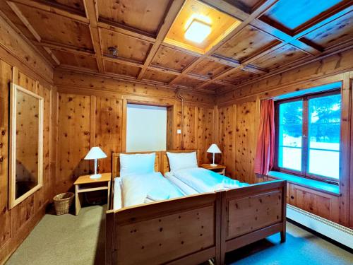 a bedroom with a bed in a wooden room at Veja Alvra 18 - Cadisch in Bergün