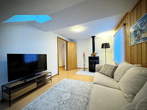 a living room with a couch and a flat screen tv at Veja Alvra 18 - Cadisch in Bergün