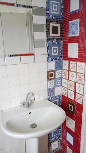 a white sink in a bathroom with red and blue tiles at Le Moulin aux Chandelles, gîtes sans ondes ajoutées ni ajoutables "Le Bois du Sanglier" in Le Vigan