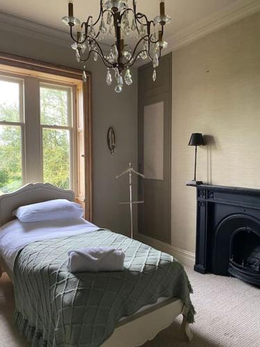 a bedroom with a bed with a fireplace and a chandelier at Home Farm Cottage in Lytham St Annes