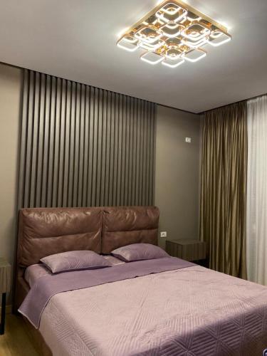 a bedroom with a large bed and a chandelier at DiMarla Apartment in Tirana