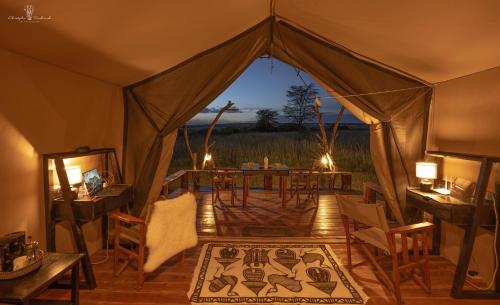 a tent with a table and chairs in it at Mara Major Camp in Masai Mara