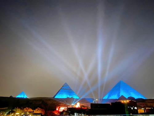 una fontana di fronte alle piramidi di notte di Pyramids Express View HoTeL a Il Cairo