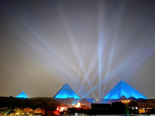 a fountain in front of the pyramids at night at Pyramids Express View HoTeL in Cairo