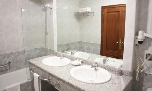 baño con 2 lavabos y espejo grande en Motel Punta Cana en Santiago de Compostela