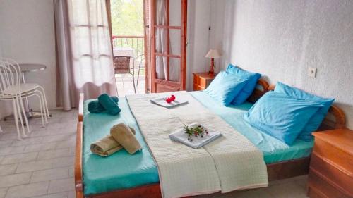 Un dormitorio con una cama con almohadas azules y una mesa. en HOTEL AGNI -ENOIKIAZOMENA DIAMERIZMATA, en Kallithea Halkidikis