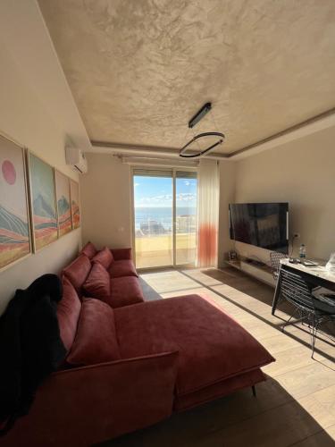 un salon avec un grand canapé rouge et une télévision dans l'établissement Sunset Sea View - Premium Apartment 2BR, à Durrës