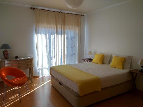 um quarto com uma cama com almofadas amarelas e uma cadeira em Casa dos Medros em São Martinho do Porto