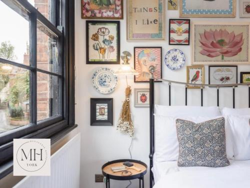 um quarto com uma cama e uma parede de quadros emoldurados em Menagerie House Luxury City Cottage, Walk Score 98 em York