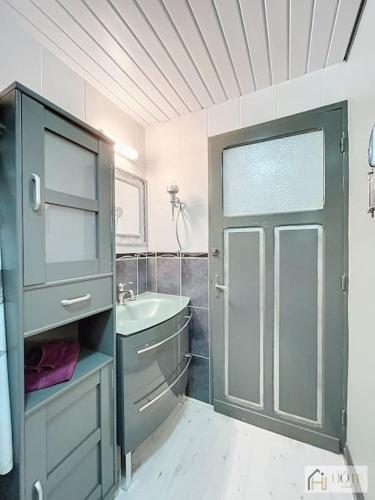 La salle de bains est pourvue d'un lavabo et d'une porte de douche. dans l'établissement Charmant Appart 3e Étage: Proche Plage & Commerces, à Bray-Dunes