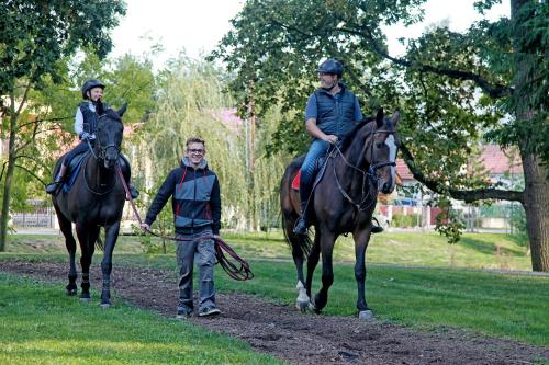 two people riding horses and a man holding a rope at Penzion Dobré Časy in Poděbrady