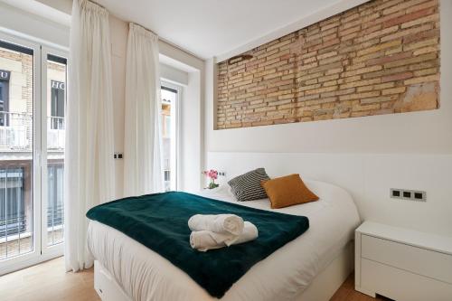 1 dormitorio con cama y pared de ladrillo en TuApartamento - Boutique Plaza del Castillo 29, en Pamplona