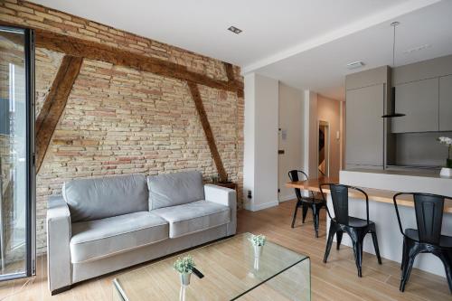 a living room with a couch and a brick wall at TuApartamento - Boutique Plaza del Castillo 29 in Pamplona