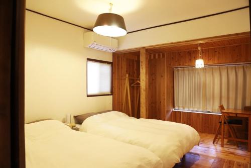 2 camas en una habitación con paredes de madera y ventana en 小宿　福右衛門邸 en Kagoshima