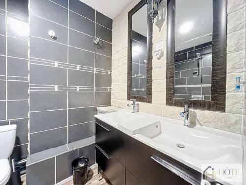 een badkamer met een wastafel, een toilet en een spiegel bij Dunes Sérénité: Calme & Confort Près Plage in Bray-Dunes