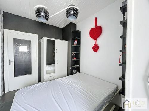 een slaapkamer met een bed en een rood hart aan de muur bij Dunes Sérénité: Calme & Confort Près Plage in Bray-Dunes