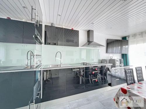 une grande cuisine avec des appareils électroménagers en acier inoxydable et des armoires noires dans l'établissement Dunes Sérénité: Calme & Confort Près Plage, à Bray-Dunes