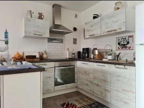 - une cuisine avec des comptoirs en marbre et des armoires blanches dans l'établissement Appartement porto pollo100 m plage, à Serra-di-Ferro