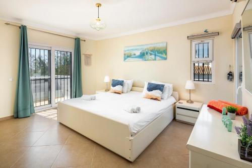 Un dormitorio con una gran cama blanca y una ventana en Villa at walking distance from center and beach!, en Carvoeiro