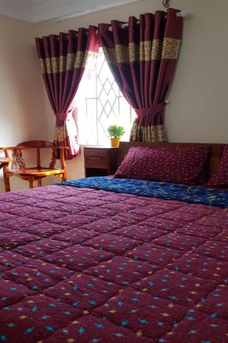 a bedroom with a bed with a purple comforter and a window at Mifa Homestay in Hương Trà