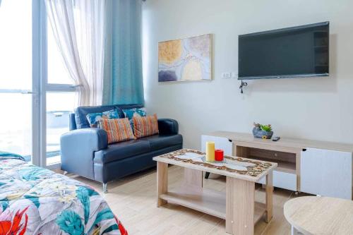 a living room with a blue couch and a tv at Jhezzstuffs staycation in Iloilo City