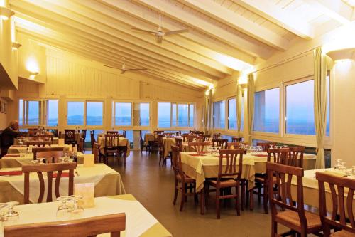 een eetkamer met tafels, stoelen en ramen bij Hotel Paola in Carloforte