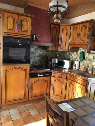 une cuisine avec des armoires en bois et une table à l'intérieur dans l'établissement La maison de Réjane, à Honfleur