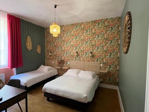 a bedroom with two beds and a wall covered in wallpaper at Logis Hôtel Le Cygne in Le Bugue