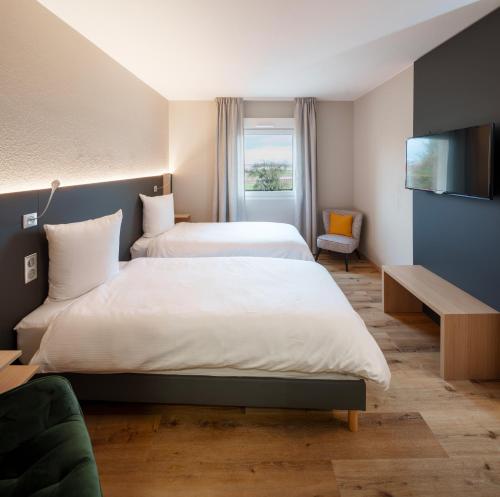 a hotel room with two beds and a television at Hôtel Restaurant Ritter'hoft in Morsbronn-les-Bains