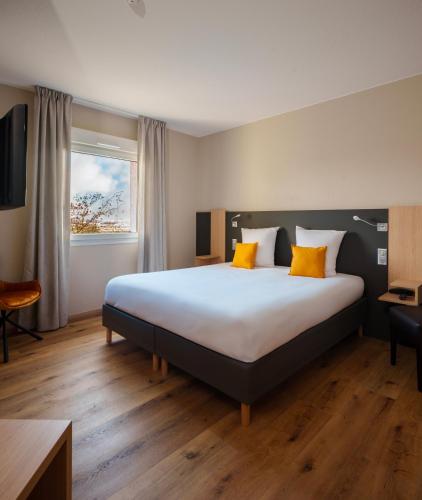 a hotel room with a large bed with yellow pillows at Logis Hôtel Restaurant Ritter'Hoft in Morsbronn-les-Bains