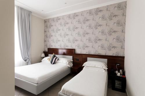 two beds in a hotel room with wallpaper at Esposizione Boutique in Rome