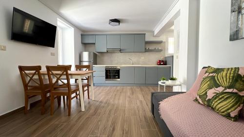 cocina y sala de estar con mesa y sillas en Spyros Stone Apartment en Lazaráta