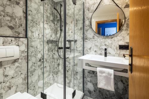 a bathroom with a shower and a sink and a mirror at Hotel Königssee in Schönau am Königssee