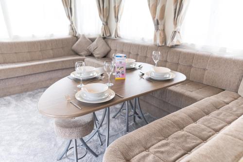 a table with glasses and plates on it with a couch at Marine Holiday Park in Rhyl