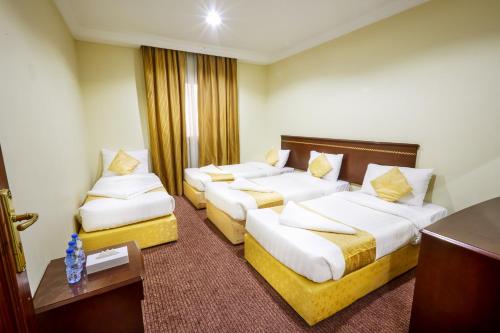 een hotelkamer met drie bedden en een tafel bij Hotel Apartments in Mekka