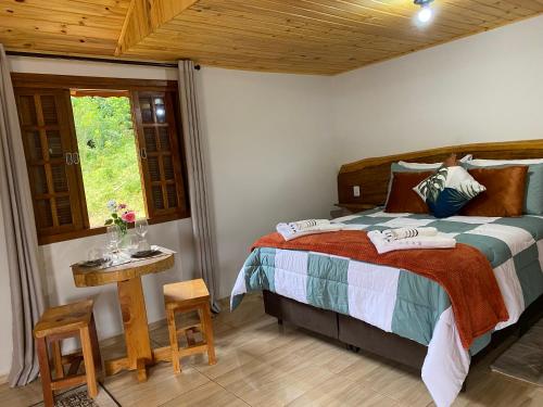 a bedroom with a bed and a table and a window at Chalé Recanto Belo. in São Mateus
