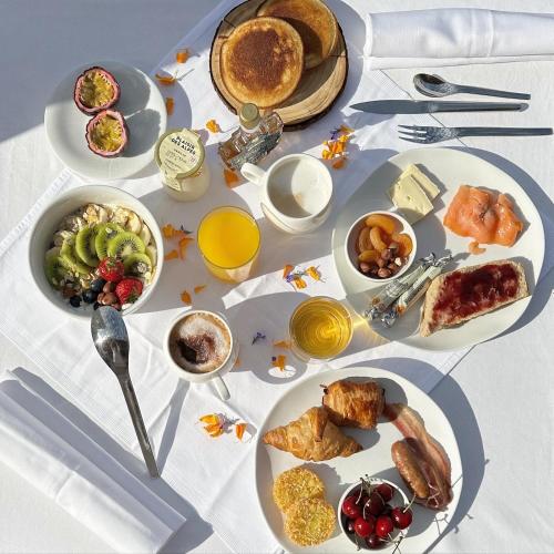 Una mesa cubierta con platos de desayuno y bebidas. en Hotel Le V de Vaujany, en Vaujany