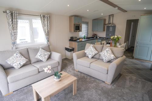 a living room with two couches and a kitchen at Marine Holiday Park in Rhyl