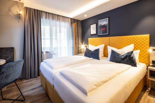 a bedroom with a large bed with a yellow headboard at Hotel Königssee in Schönau am Königssee