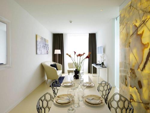 a white dining room with a table and chairs at VISIONAPARTMENTS Wolframplatz - contactless check-in in Zürich